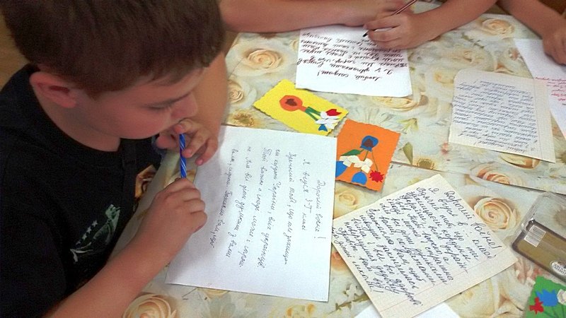 Маленький хлопчик пише листа захиснику Укра_ни