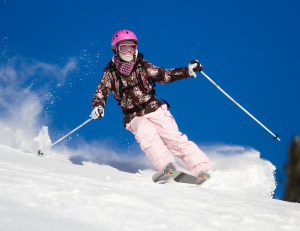 Girl riding on skis with bright blue sky on the background